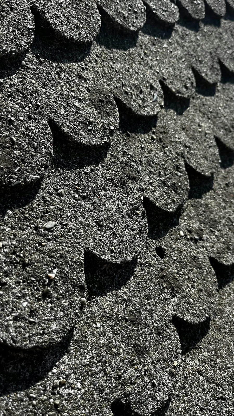 Black scalloped shingle edges and mineral granules in extreme close-up