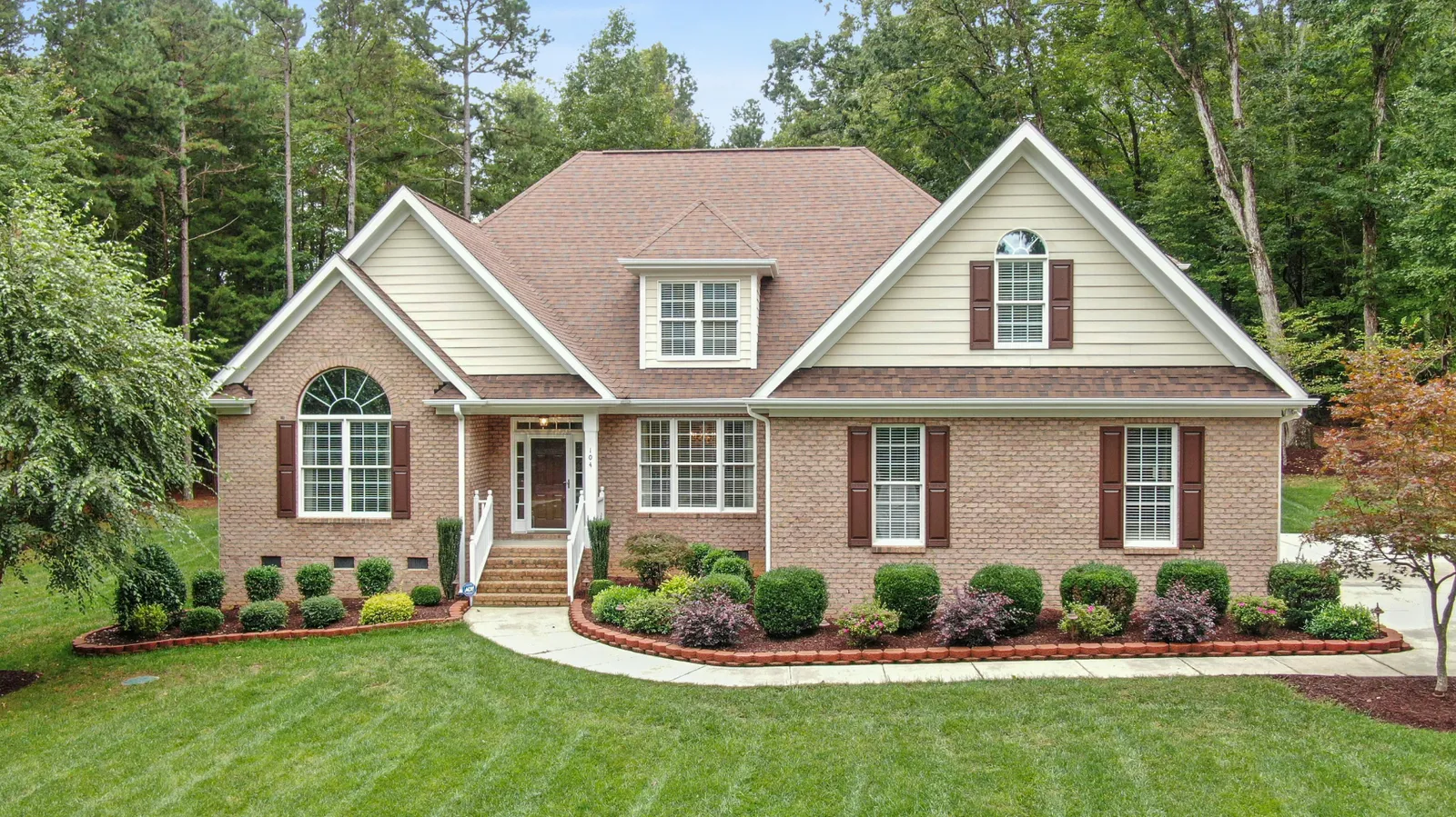 Brown architectural shingle roof on a brick home with an arched window
