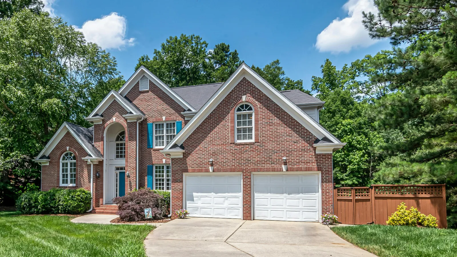 Two garage doors on a brick two-story home under a gray shingle roof