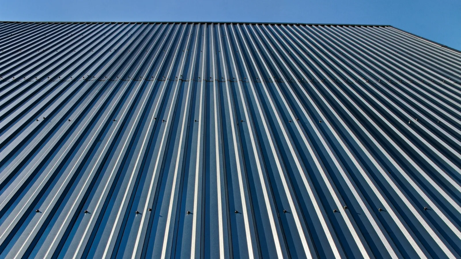 Upward view of ribbed metal cladding against a clear sky